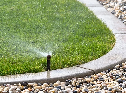 Arroseur automatique pulvérisant de l'eau sur une pelouse verte fraîchement tondue à Allainville près d'Ablis dans les Yvelines 78