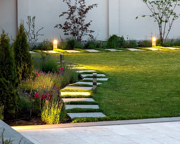 Jardin paysager moderne au crépuscule avec allée éclairée et parterres de fleurs à Allainville près d'Ablis dans les Yvelines 78