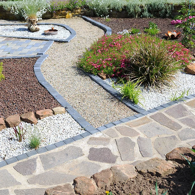 Allée de jardin sinueuse en pierre et gravier avec des parterres de fleurs colorés à Allainville près d'Ablis dans les Yvelines 78