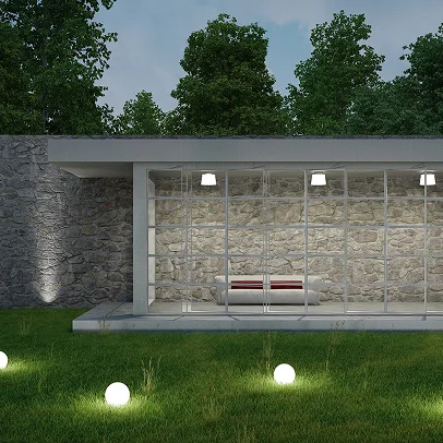 Patio moderne avec murs en pierre, canapé vitré, et globes lumineux sur pelouse à Allainville près d'Ablis dans les Yvelines 78