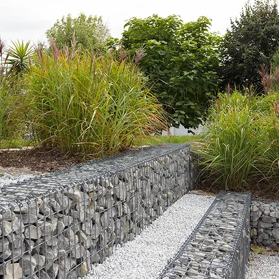 Mur de gabions remplis de pierres, bordant un sentier de gravier et des plantations à Allainville près d'Ablis dans les Yvelines