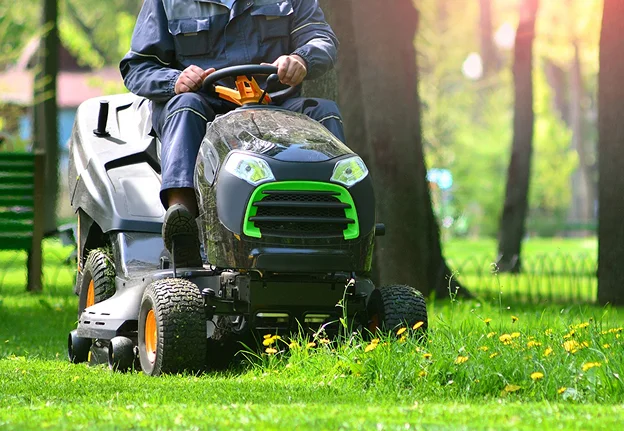 Homme tondant la pelouse avec une tondeuse autoportée sous le soleil à Allainville près d'Ablis dans les Yvelines 78