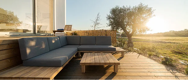 Terrasse en bois avec canapé sectionnel et table basse, vue sur la campagne ensoleillée à Allainville près d'Ablis dans les Yvelines 78
