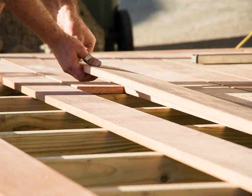 Mains posant des planches de bois sur une structure de terrasse en construction à Allainville près d'Ablis dans les Yvelines 78